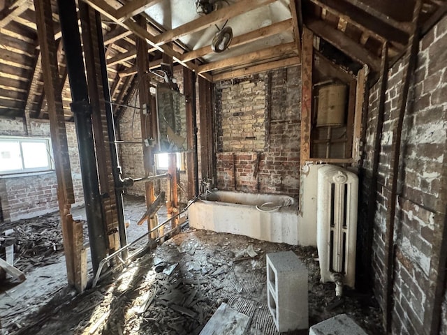 misc room featuring radiator and brick wall