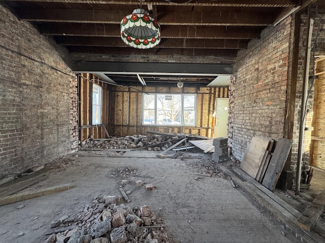 misc room featuring brick wall and beam ceiling