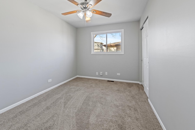 carpeted empty room featuring visible vents, baseboards, and a ceiling fan