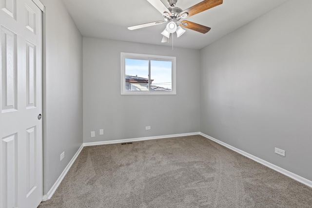 carpeted spare room with visible vents, ceiling fan, and baseboards