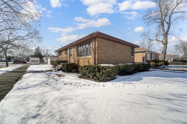 view of snowy exterior with brick siding