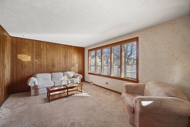 living room with light carpet, wood walls, a textured ceiling, and baseboards