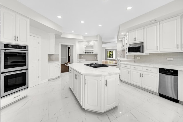 kitchen with recessed lighting, a kitchen island, white cabinets, marble finish floor, and appliances with stainless steel finishes