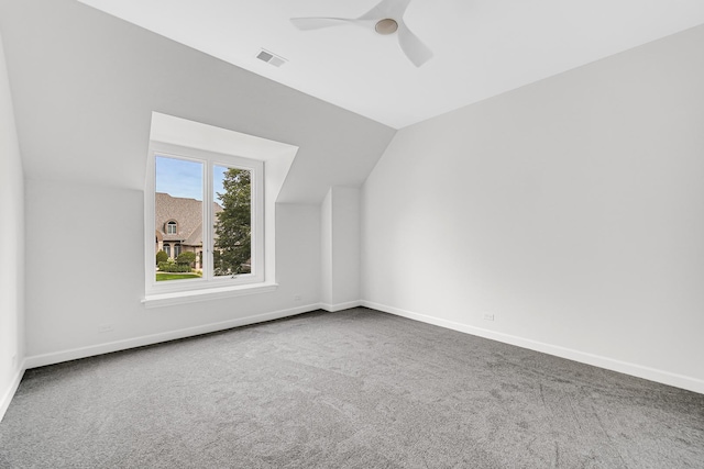 additional living space featuring carpet floors, visible vents, a ceiling fan, vaulted ceiling, and baseboards