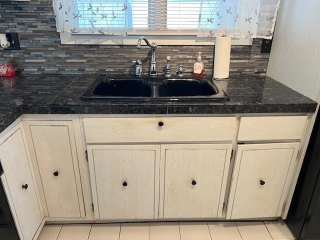 kitchen with tasteful backsplash, light tile patterned flooring, a sink, and light brown cabinets