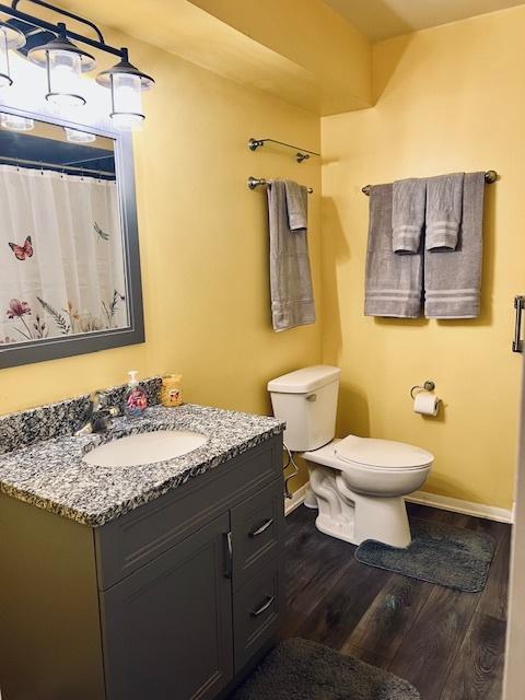 full bath featuring baseboards, vanity, toilet, and wood finished floors