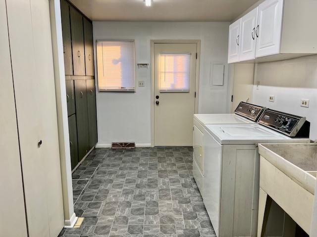 washroom featuring cabinet space, baseboards, stone finish floor, separate washer and dryer, and a sink