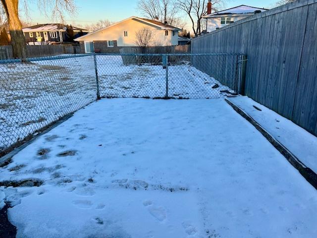 yard layered in snow with a fenced backyard