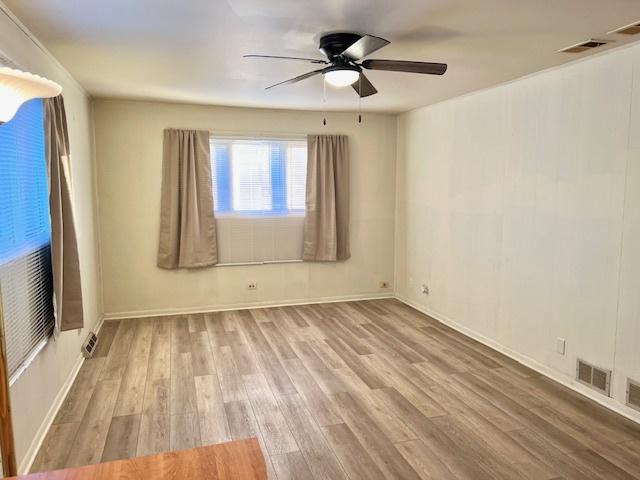 spare room with light wood-style floors, baseboards, visible vents, and a ceiling fan