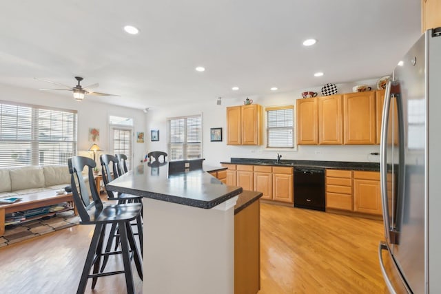 kitchen featuring a breakfast bar, freestanding refrigerator, black dishwasher, and dark countertops