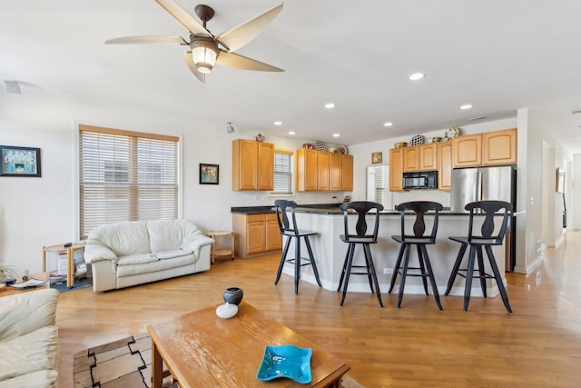 living room featuring a ceiling fan, recessed lighting, and light wood-style flooring