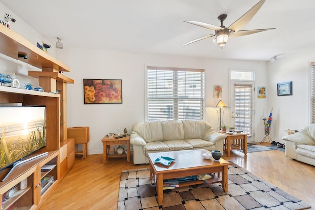 living area featuring light wood-style floors, baseboards, and a ceiling fan