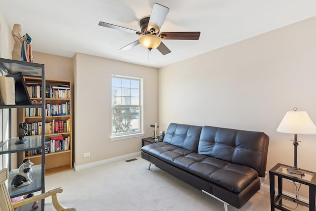 living room featuring light colored carpet, ceiling fan, visible vents, and baseboards