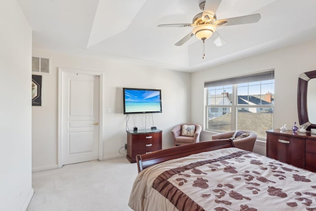 bedroom with visible vents, baseboards, light colored carpet, ceiling fan, and a tray ceiling