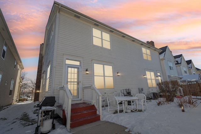 back of house at dusk with entry steps and central air condition unit