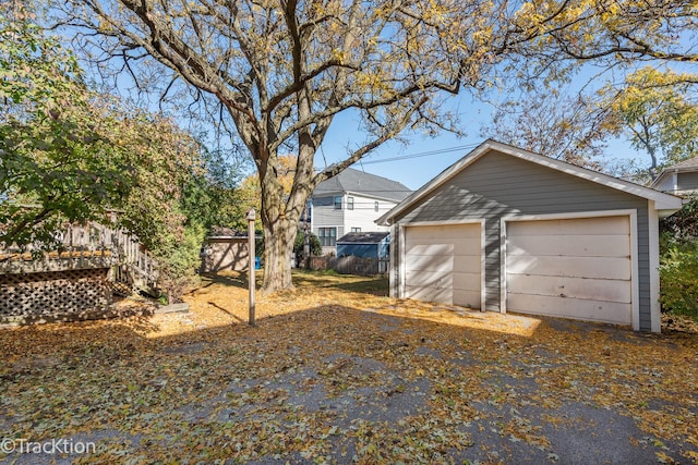 exterior space featuring a detached garage, fence, and an outbuilding