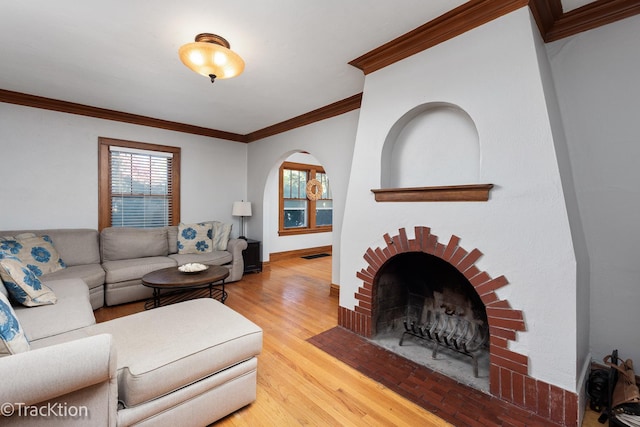 living area with visible vents, ornamental molding, a brick fireplace, wood finished floors, and baseboards