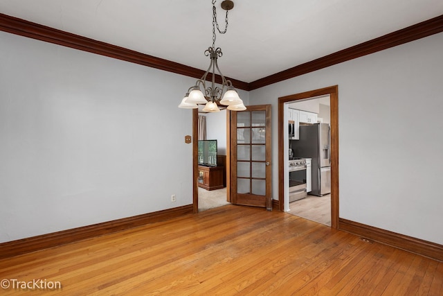 spare room featuring ornamental molding, light wood-style flooring, and baseboards