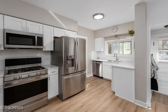 kitchen with a sink, white cabinetry, light countertops, appliances with stainless steel finishes, and decorative backsplash