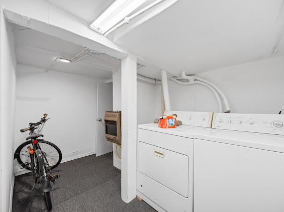 washroom featuring heating unit, laundry area, dark carpet, and washer and dryer