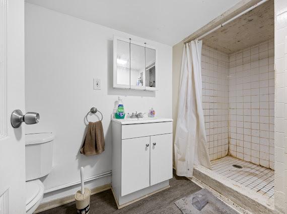 bathroom with toilet, a shower stall, vanity, and baseboards