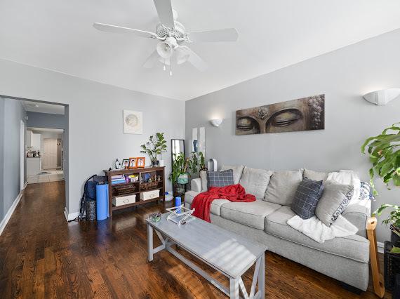 living room with a ceiling fan, dark wood finished floors, and baseboards