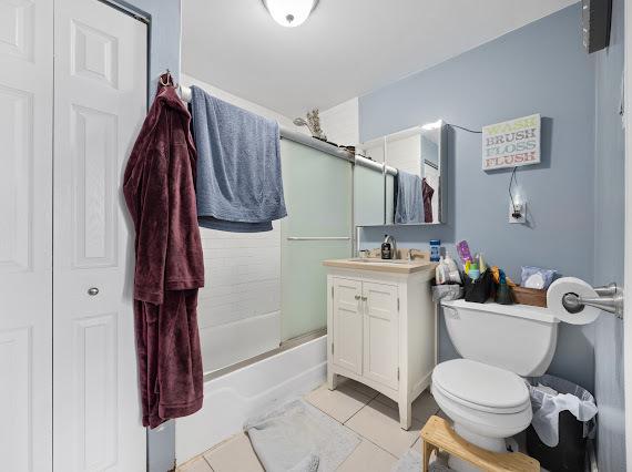 bathroom with tile patterned flooring, a closet, vanity, and bath / shower combo with glass door