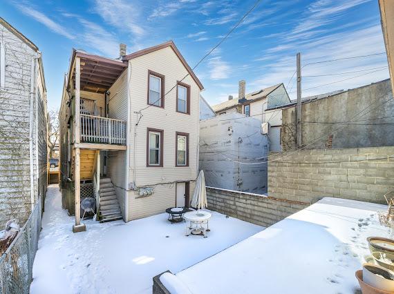 snow covered rear of property with fence