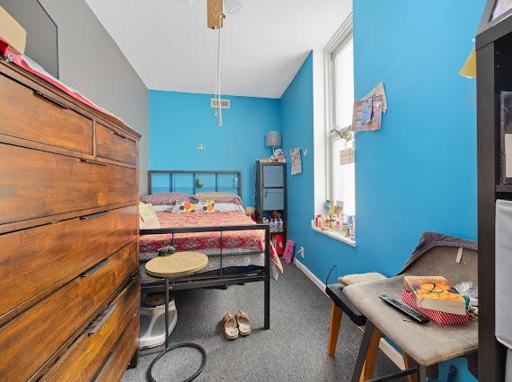 carpeted bedroom with a ceiling fan, multiple windows, and baseboards