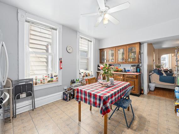 dining space with ceiling fan, baseboards, and a healthy amount of sunlight