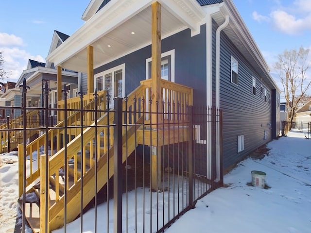 view of snowy exterior featuring a porch and fence