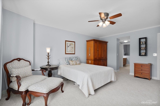 bedroom with light colored carpet, a ceiling fan, baseboards, ensuite bath, and crown molding