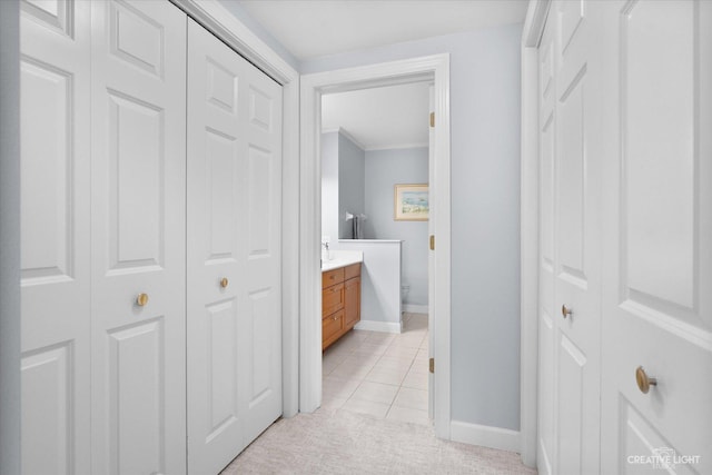 bathroom featuring crown molding, a closet, vanity, baseboards, and tile patterned floors