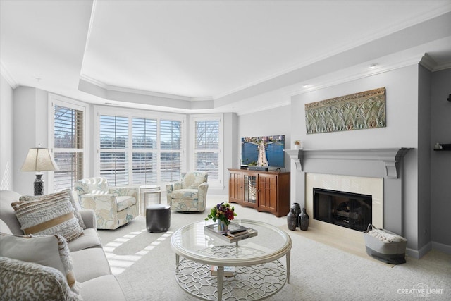 carpeted living room featuring baseboards, ornamental molding, a tray ceiling, and a high end fireplace