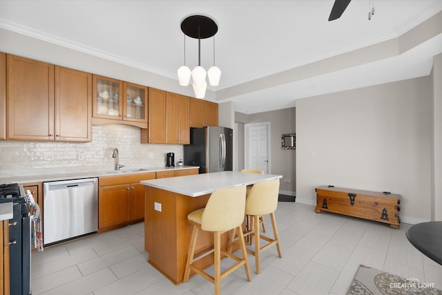 kitchen with a sink, light countertops, appliances with stainless steel finishes, a center island, and glass insert cabinets