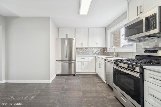 kitchen with light countertops, decorative backsplash, appliances with stainless steel finishes, white cabinets, and baseboards