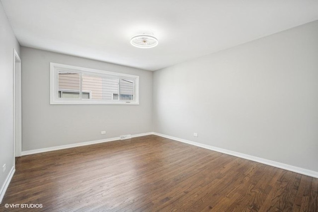 empty room featuring dark wood finished floors and baseboards