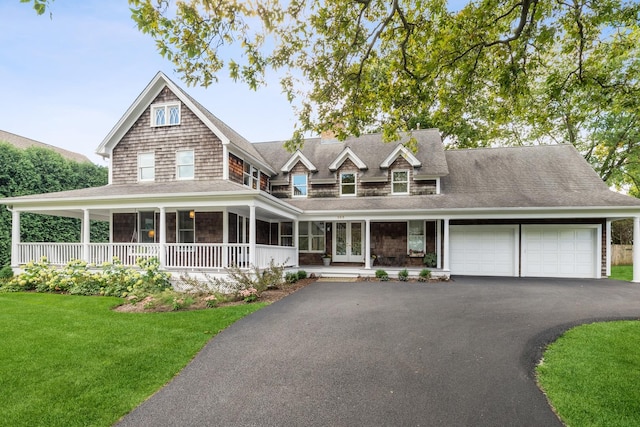 view of front of home featuring an attached garage, covered porch, driveway, french doors, and a front yard