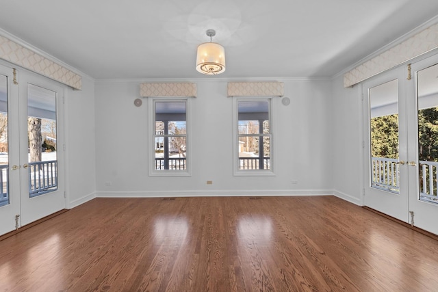 unfurnished room featuring baseboards, french doors, wood finished floors, and crown molding