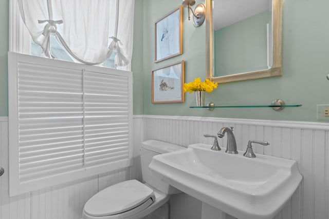 bathroom with toilet, a sink, and wainscoting