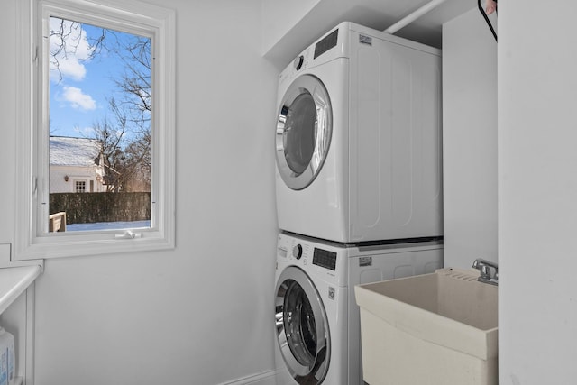 laundry room featuring laundry area, stacked washing maching and dryer, and a sink