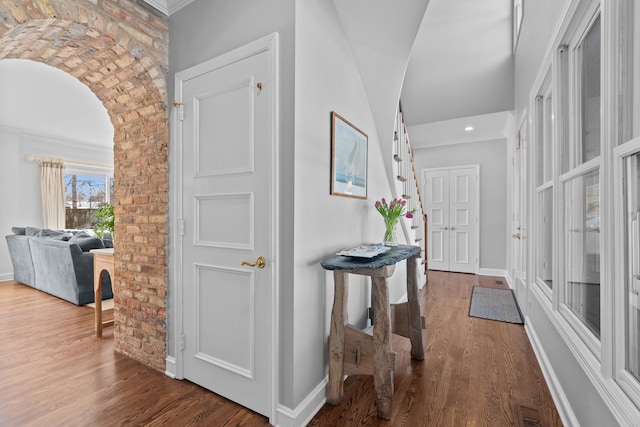 interior space featuring baseboards, visible vents, arched walkways, and wood finished floors
