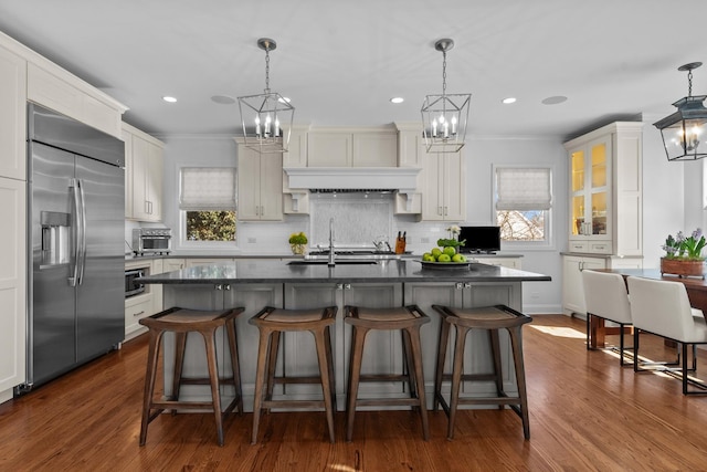 kitchen with a healthy amount of sunlight, dark countertops, built in fridge, and a notable chandelier