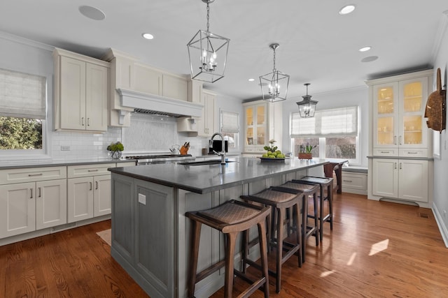 kitchen with decorative backsplash, crown molding, a sink, and exhaust hood