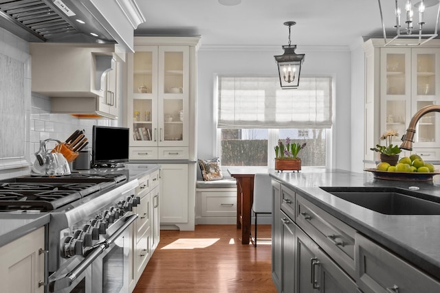 kitchen with range with two ovens, custom exhaust hood, crown molding, pendant lighting, and a sink