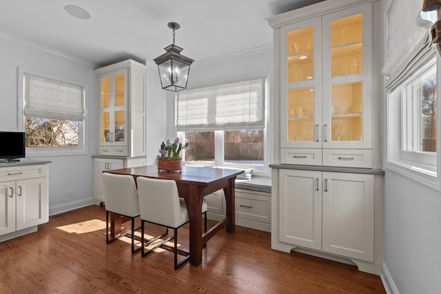 dining area featuring a chandelier, ornamental molding, dark wood-type flooring, and baseboards