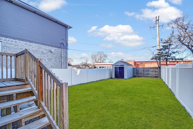 view of yard with a deck, an outbuilding, a fenced backyard, a storage shed, and stairway