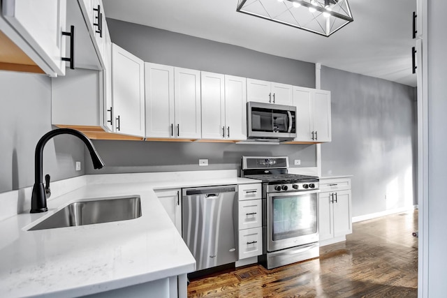 kitchen featuring appliances with stainless steel finishes, white cabinets, light countertops, and a sink