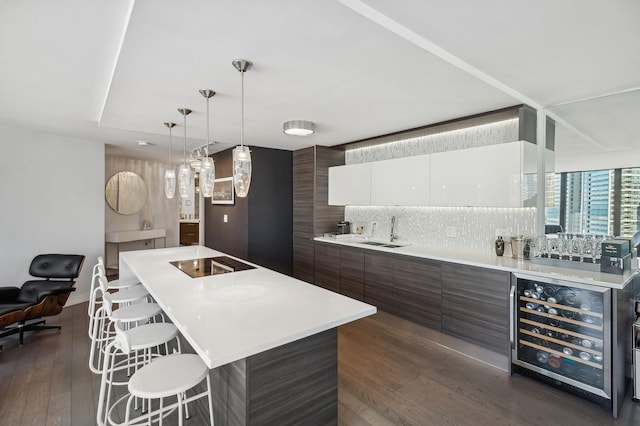 kitchen with dark brown cabinetry, white cabinets, light countertops, modern cabinets, and a center island with sink