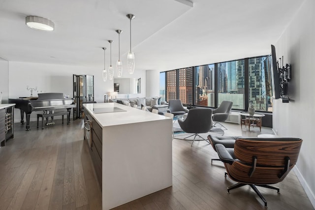 kitchen featuring open floor plan, light countertops, hanging light fixtures, dark wood-style floors, and an island with sink